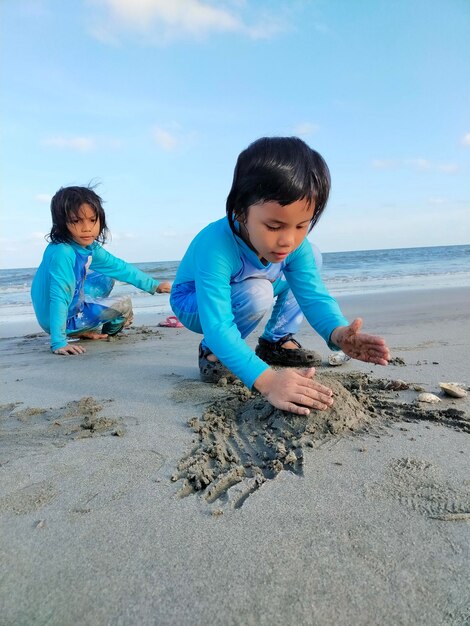 Foto irmãos de pé na praia contra o céu