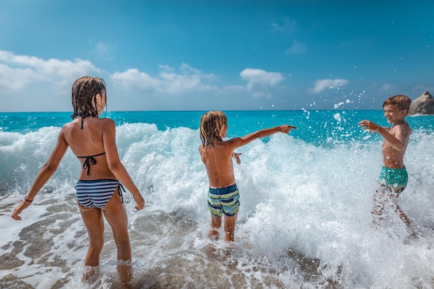 Irmãos e irmãs brincando na praia durante o dia quente de férias de verão.