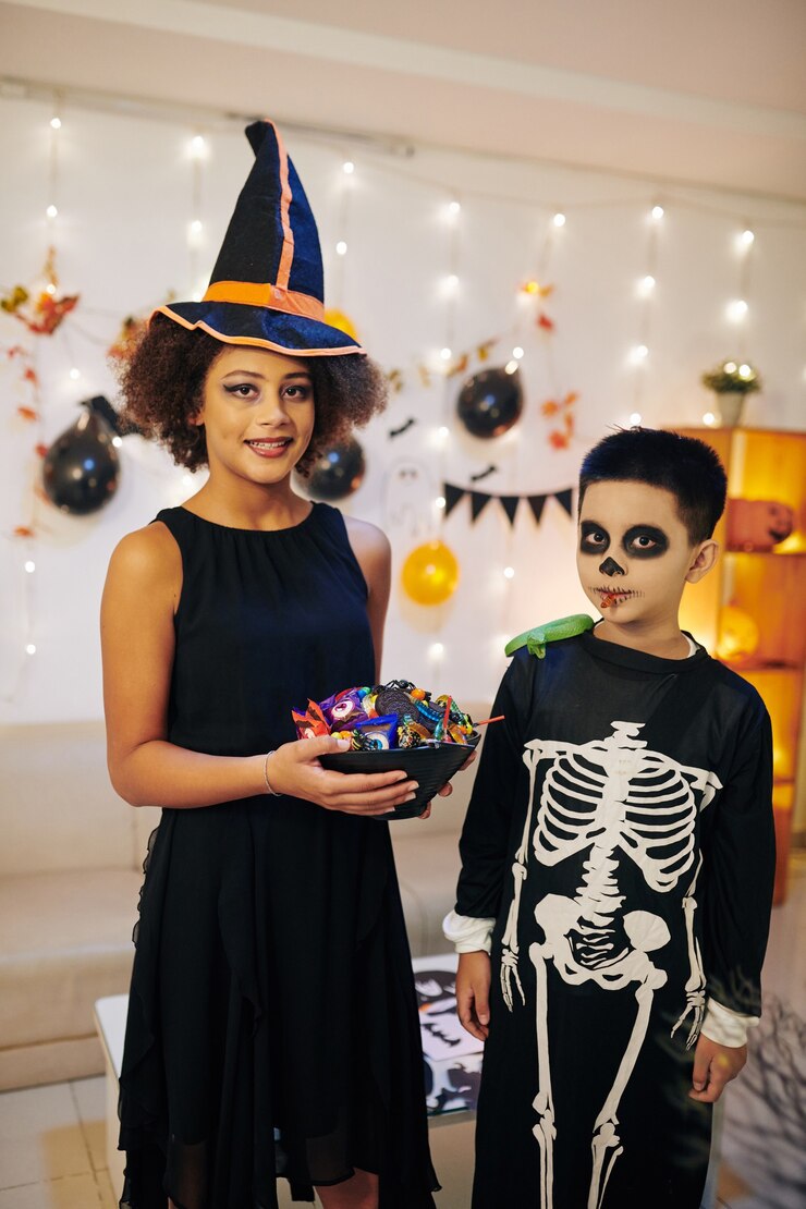 Foto irmãos e irmãs sorridentes em clientes de halloween segurando uma tigela de doces preparados para doces ou travessuras