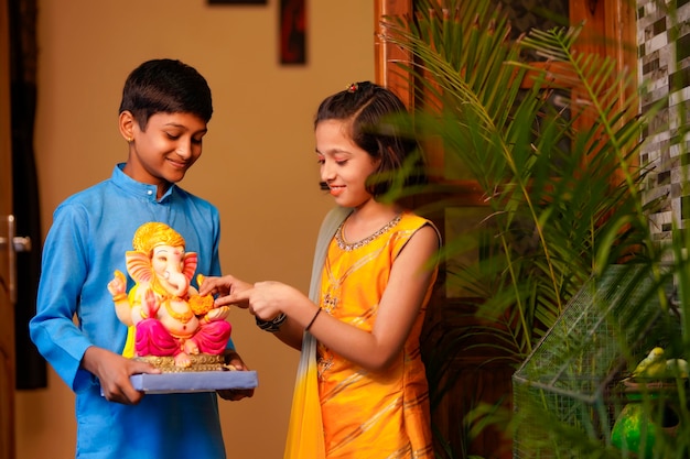 Irmãos indianos pequenos com o senhor ganesha.