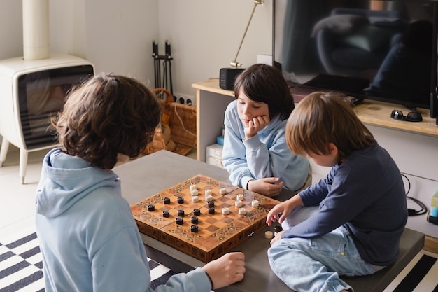 Irmãos jogando damas em casa irmãos jogando o jogo de estratégia de tabuleiro passando tempo juntos