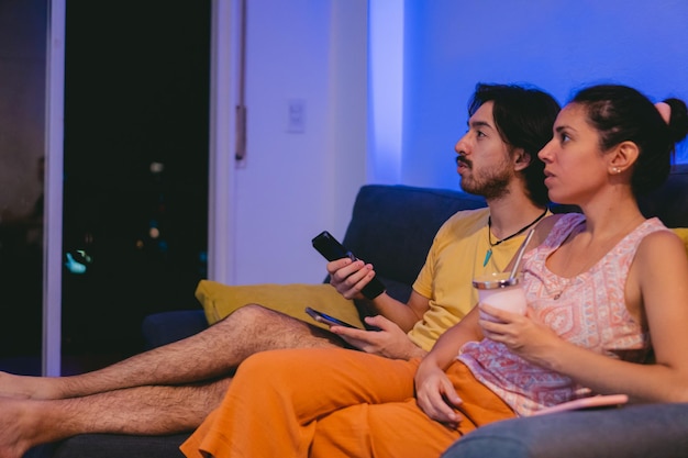 Irmãos latinos flagrados assistindo TV no sofá de casa enquanto tomavam mate Copiar espaço