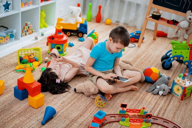 Irmãos no chão brincando com smartphones