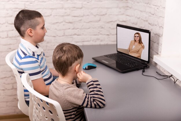 Irmãos olhando para o laptop enquanto aprendem na sala das crianças.