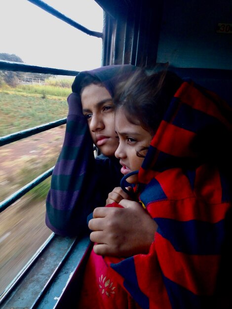Foto irmãos olhando pela janela enquanto estão sentados no trem