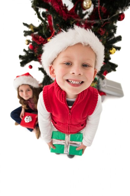 Irmãos pequenos festivos sorrindo na câmera segurando presentes