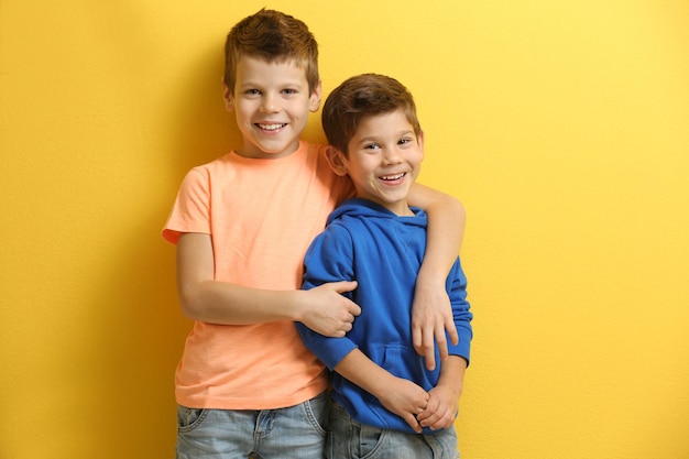 Irmãozinhos bonitos em pé no fundo amarelo