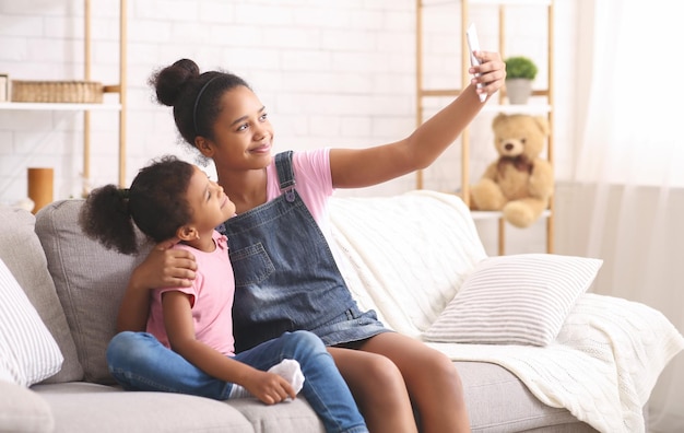 Irmãs africanas tirando selfie em smartphone em casa