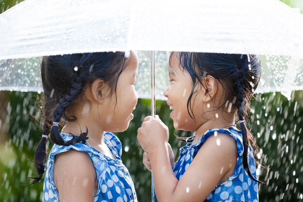 Irmãs com guarda-chuva se divertindo brincando na chuva