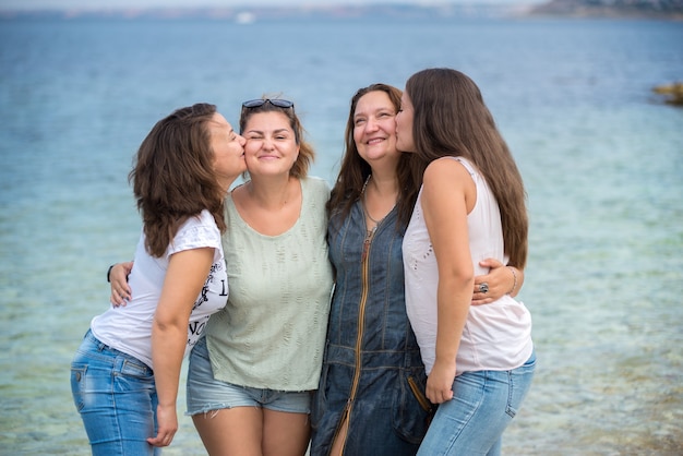 Irmãs da família felizes em pé sobre um pontão de madeira em frente ao mar no verão.