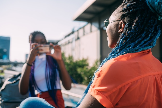 Irmãs de duas mulheres ao ar livre usando telefone inteligente tirando fotos