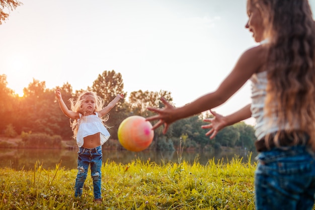 Irmãs de meninas brincando com bola no parque de verão. Crianças se divertindo ao ar livre.