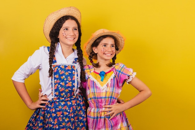 Irmãs e amigas com roupas típicas da festa junina abraçadas com as mãos na cintura para a festa do arraia