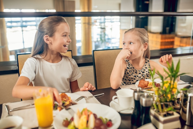 Irmãs. Irmãos fofos sentados à mesa tomando café da manhã