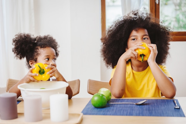 Irmãzinha mais nova e fofa parecendo imaginando e imitando a irmã mais velha tentando comer pimentão