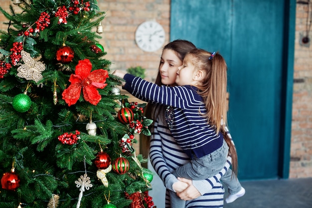 Irmãzinha que decora uma árvore de Natal. O conceito de Cristo