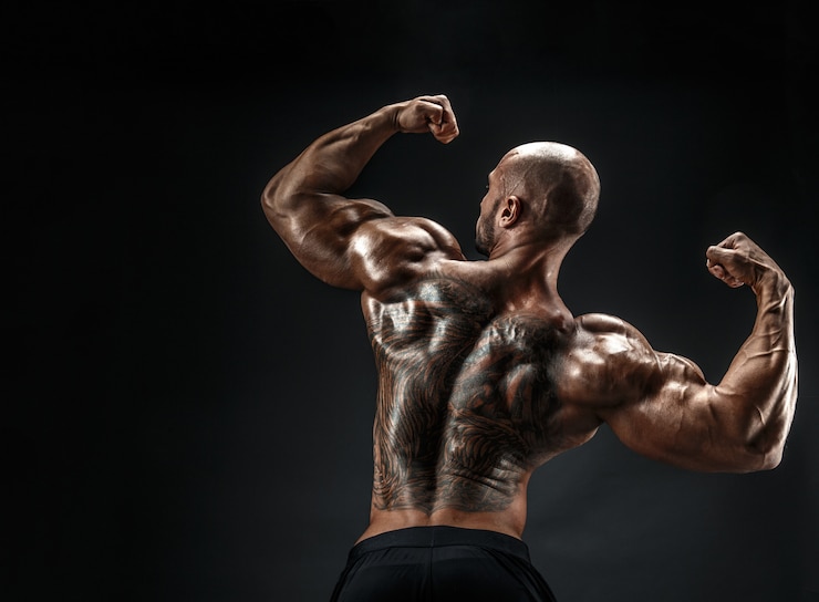 Foto irreconhecível homem musculoso com tatuagem nas costas contra de fundo preto. isolado.