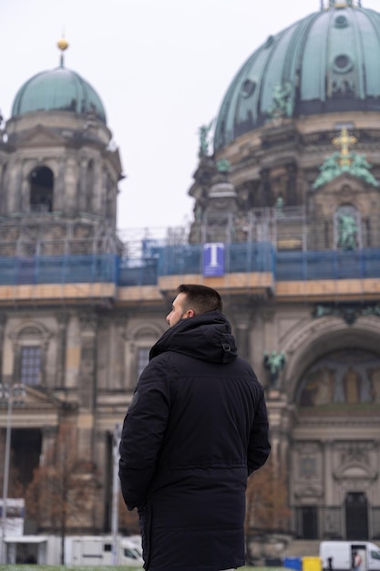 Irreconhecível jovem turista masculino no parque em frente à Catedral de Berlim com neve por todo o chão