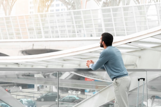 Irreconocible viajero masculino de Oriente Medio de pie con maleta en el aeropuerto