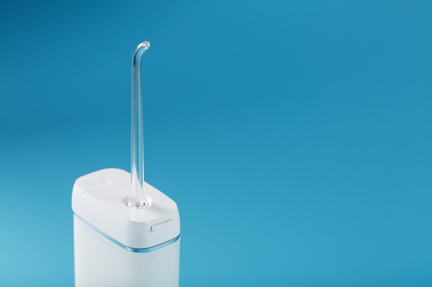Foto irrigador móvel para limpar a cavidade oral em uma superfície azul
