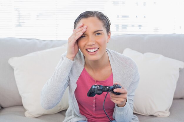 Irritada mujer bonita sentada en el sofá jugando videojuegos