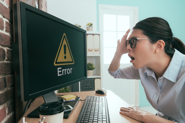 Foto irritado gerente da empresa senhora encontrando escritório trabalhando computador recebendo problema de erro mostrando símbolo de erro sentindo-se irritado e confuso.