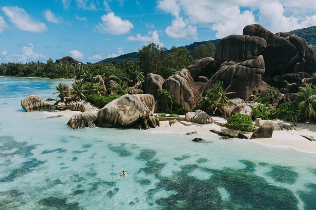 Isla "La digue" en Seychelles. Playa de plata con piedra granítica y selva. Hombre disfrutando de vacaciones en la playa y divertirse con kayak. Vista aérea