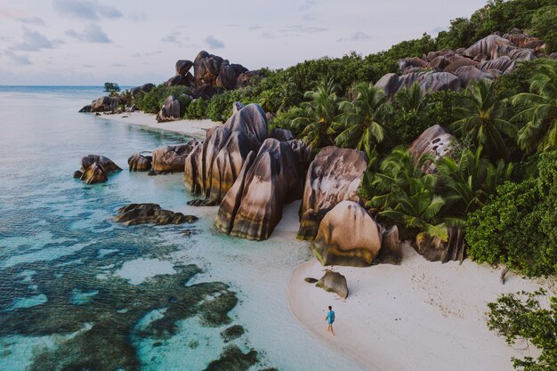 Isla "La digue" en Seychelles. Playa de plata con piedra granítica y selva. Hombre disfrutando de vacaciones y relajarse en la playa. Vista aérea