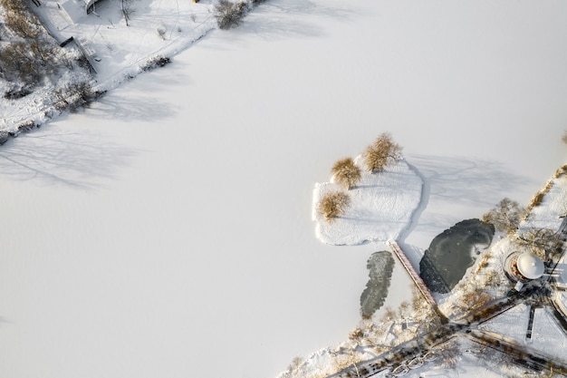 Isla en un lago con un puente en el Parque Loshitsky de invierno Minsk, Bielorrusia