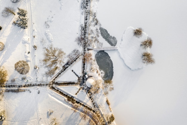 Una isla en un lago con un puente en Winter Loshitsky Park Minsk