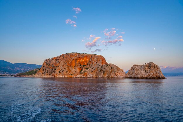 Una isla rocosa en el agua con la puesta de sol detrás de ella