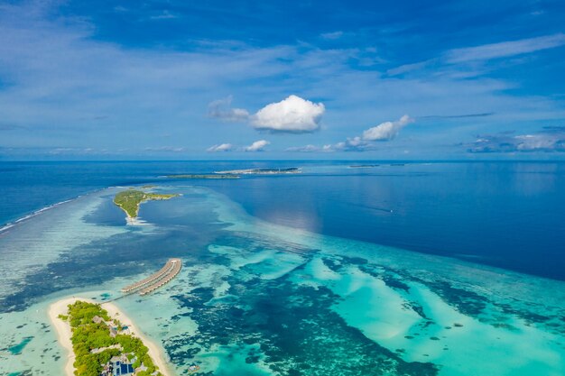 Isla turística de lujo en Maldivas con fondo de villas de agua y mar y cielo azul, vista aérea