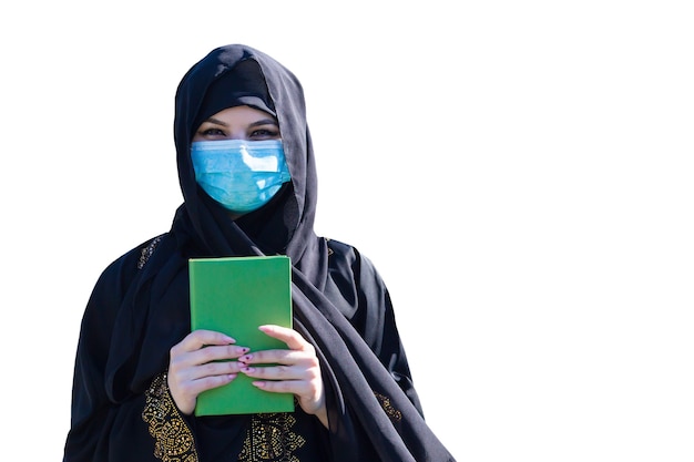 Islamische Frau mit dem Koran in den Händen. Medizinische Schutzmaske