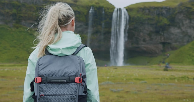 Islandia viaje al aire libre Mujer con mochila cerca de la cascada de Seljalandsfoss