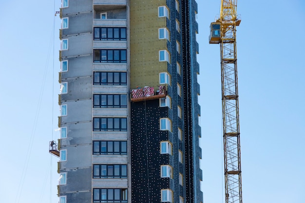 Isolamento térmico de edifício residencial de vários andares em construção com guindaste de torre.