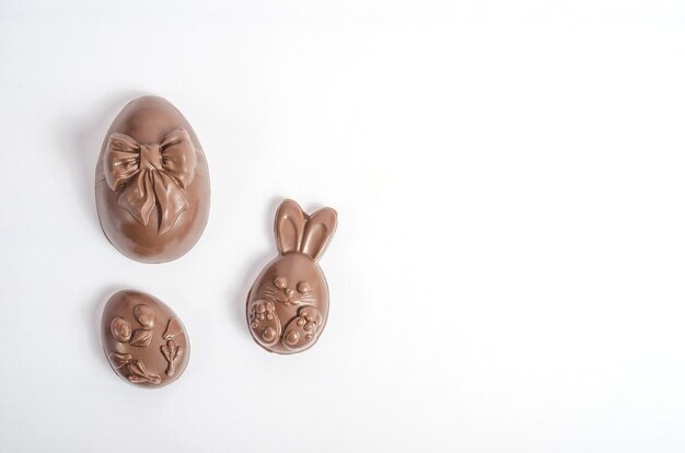 Isolieren Sie Schokoladen-Ostereier in Form eines Kaninchens und eines Huhns auf einem weißen Hintergrund mit Kopienraum.