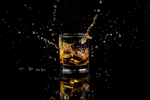 Isolierte Aufnahme von Whisky mit Spritzer auf schwarzem Hintergrund