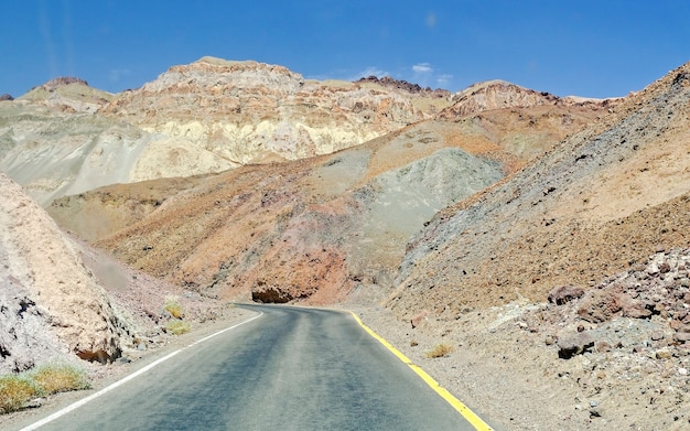 Isolierte Straße unter den Felsen in Death Valley, Kalifornien, USA