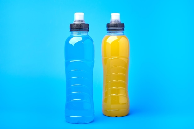 Isotonisches Energie-orange-gelbes und blaues Sportgetränk in Plastikflaschen auf gelbem Hintergrund erlaubt