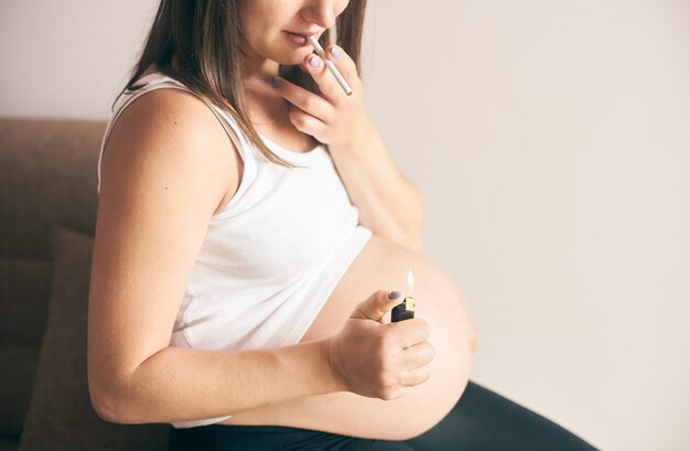 Isqueiro e cigarro nas mãos de gestante