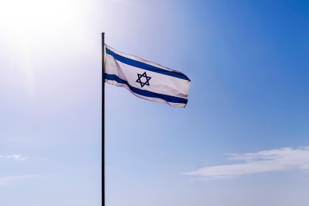 Israelische Flagge flattert an einem guten sonnigen Tag und altem Stadthintergrund im Wind