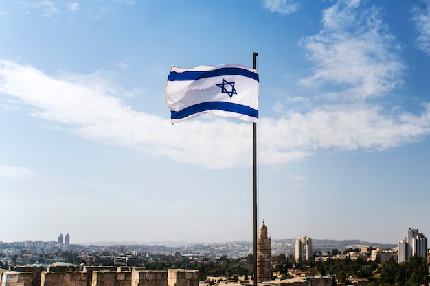 Israelische Flagge flattert an einem guten sonnigen Tag und im alten Stadthintergrund im Wind.