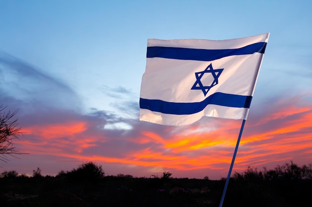 Israelische Flagge vor dem Hintergrund eines feurigen Sonnenuntergangs Gedenktag Yom HaZikaron Patriotischer Feiertag Israelischer Unabhängigkeitstag Yom Ha'atzmaut Konzept