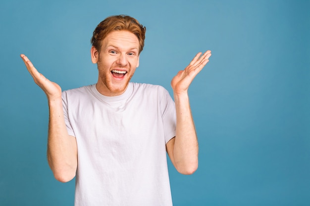 Isso! feliz vencedor! homem bonito jovem feliz comemorando a vitória, gesticulando e mantendo a boca aberta.