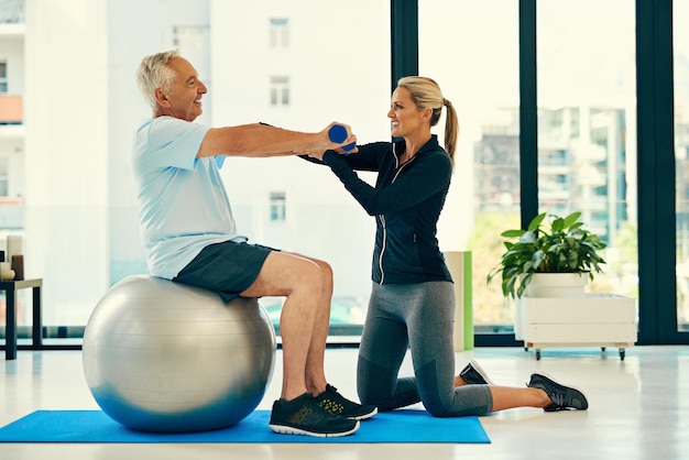 É isso, mantenha as costas retas Foto de um fisioterapeuta ajudando seu paciente sênior com seus exercícios em um centro de fitness
