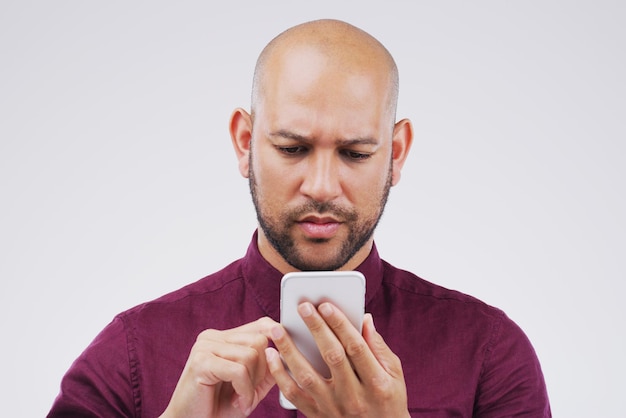 Isso não pode estar certo Foto de estúdio de um homem bonito usando seu celular contra um fundo cinza