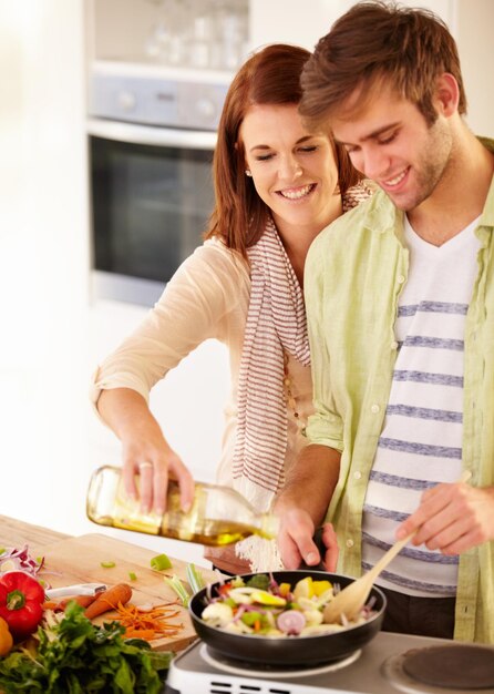 Isso precisa de mais óleo. Um casal feliz cozinhando na cozinha.