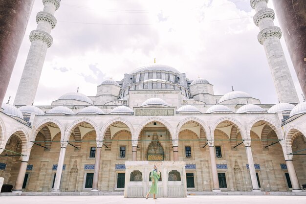 Istambul Turquia 06 de julho de 2021 Jovem viajante em um vestido verde e lenço de cabeça caminhando ao longo da Mesquita Suleymaniye em Istambul