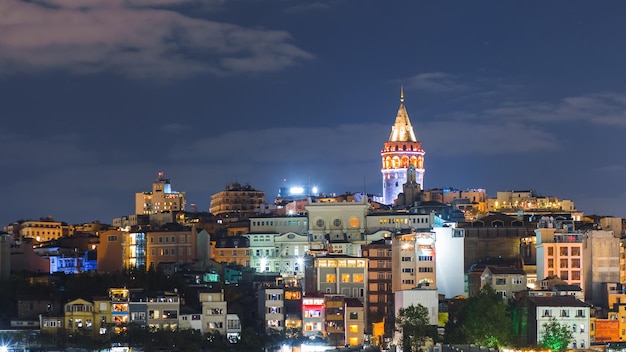 Istanbul-Stadtbild mit Galata-Turm und sich hin- und herbewegenden Touristenbooten in Bosporus-Nacht