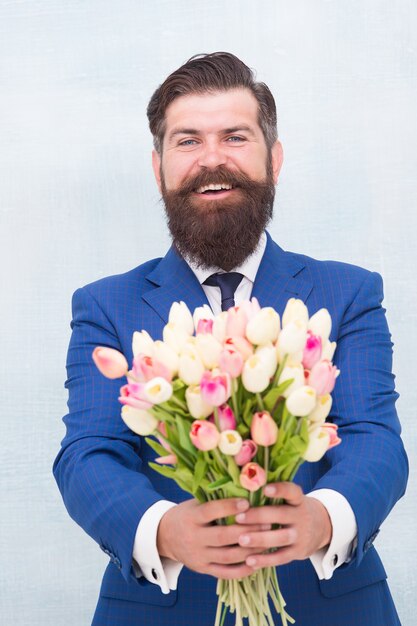 Isto é para você. Dia da Mulher. 8 de março. Presente de primavera. Hipster de homem barbudo com flores. Comemore a primavera. Fazendo surpresa. Cavalheiro com tulipas. A primavera está chegando. Saudações. Buquê de tulipa de homem barbudo.